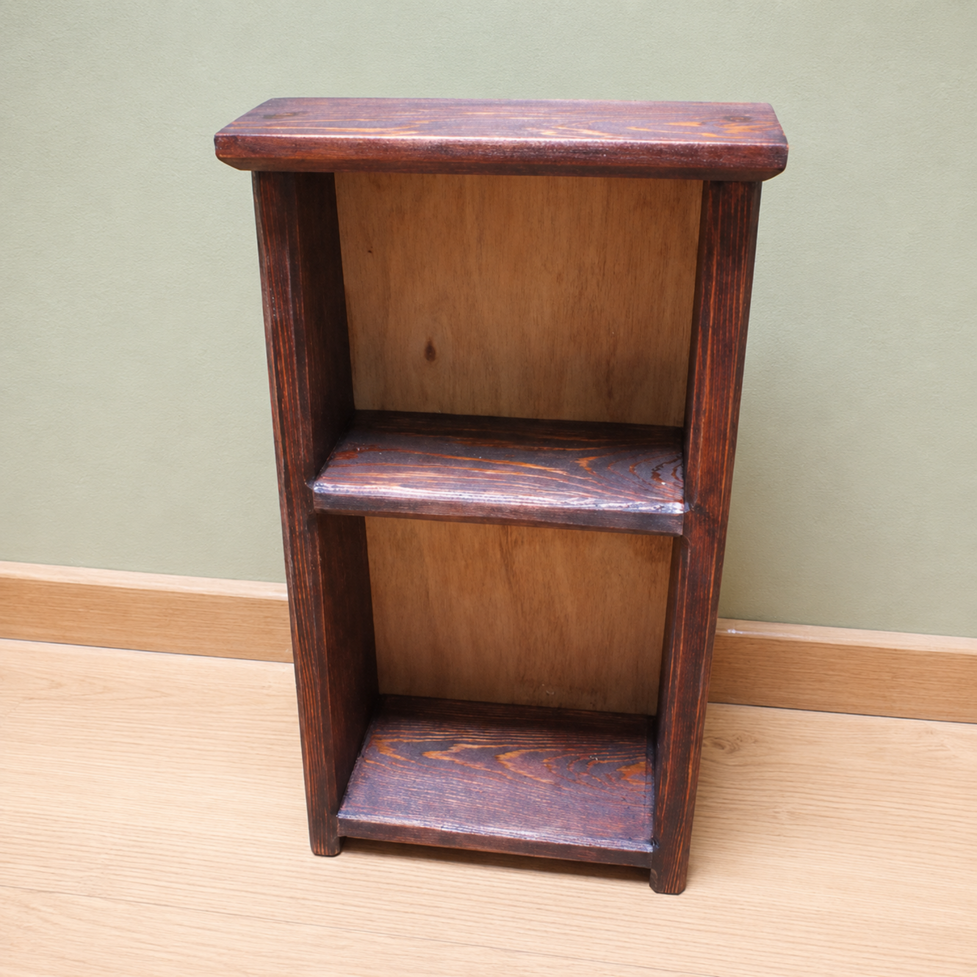 Wooden shelf with two shelves against a green wall.