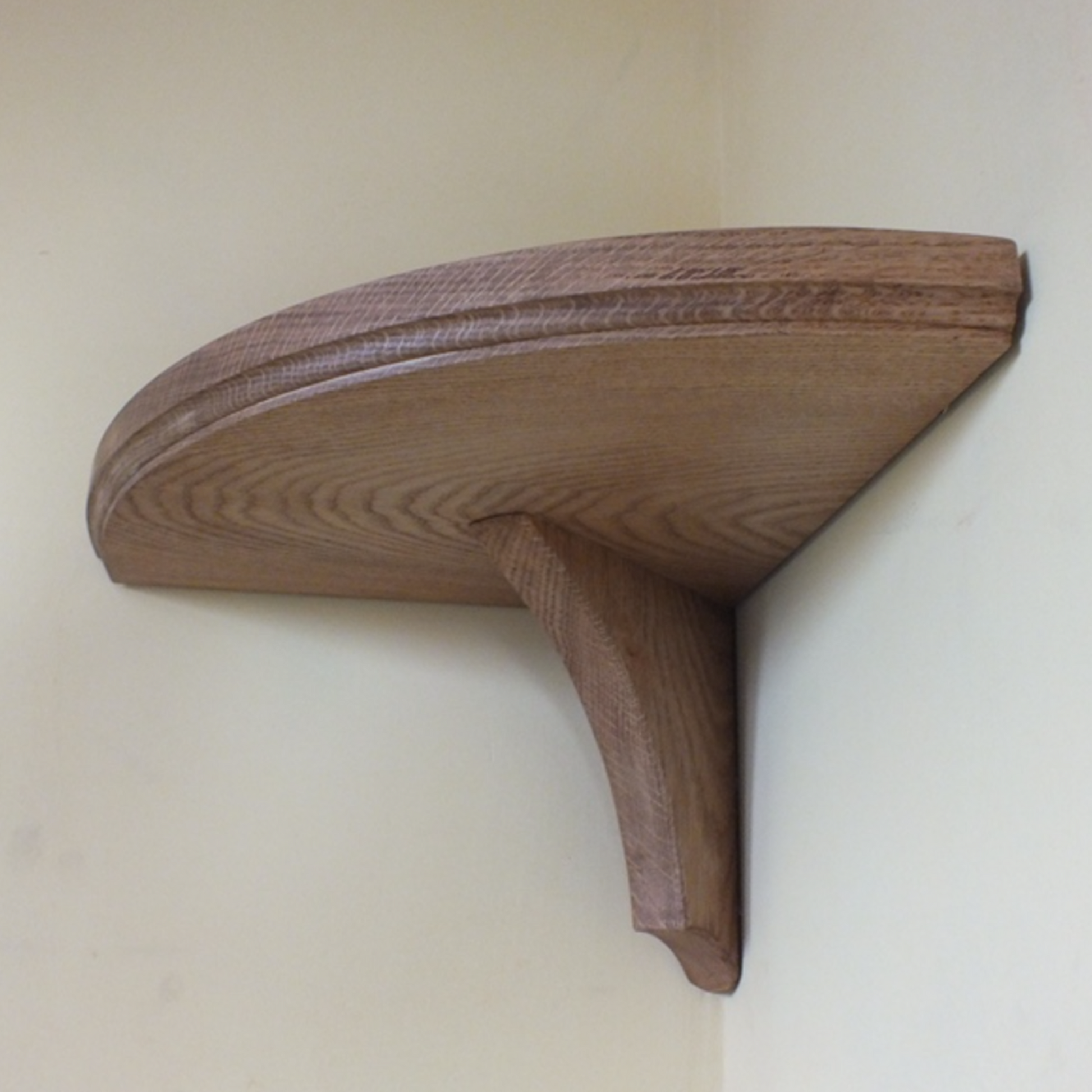 A brown oak corner shelf with a smooth finish, designed to be wall-mounted.