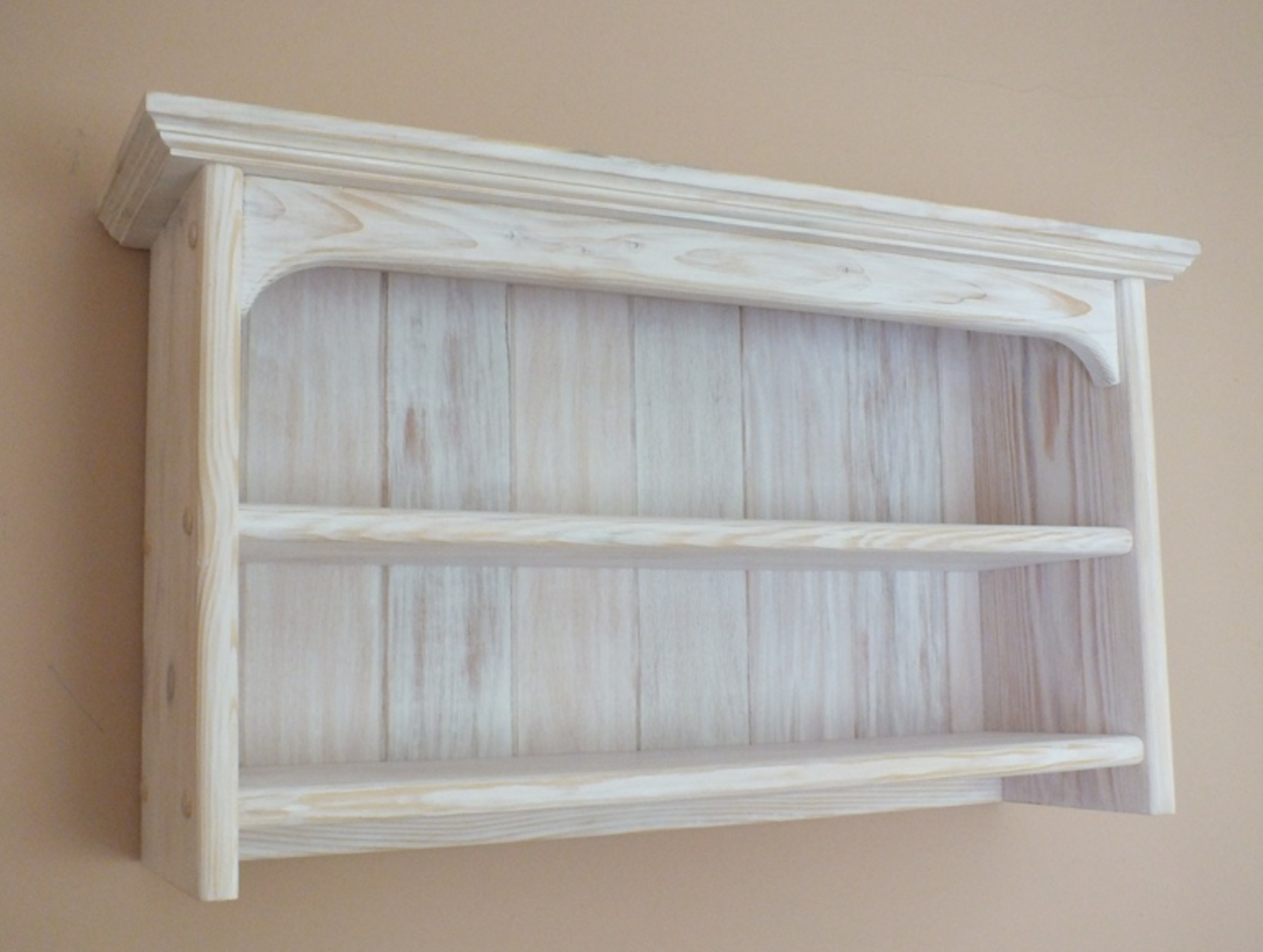 Wooden shelf with a white wash finish on a beige wall