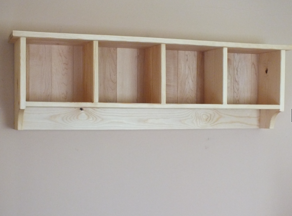 A light natural wood wall-mounted open shelf with five cubbies, shown against a plain beige wall.