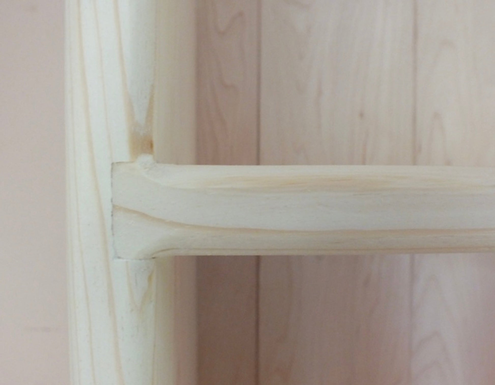 Close-up of a wooden shelf with a light pink background