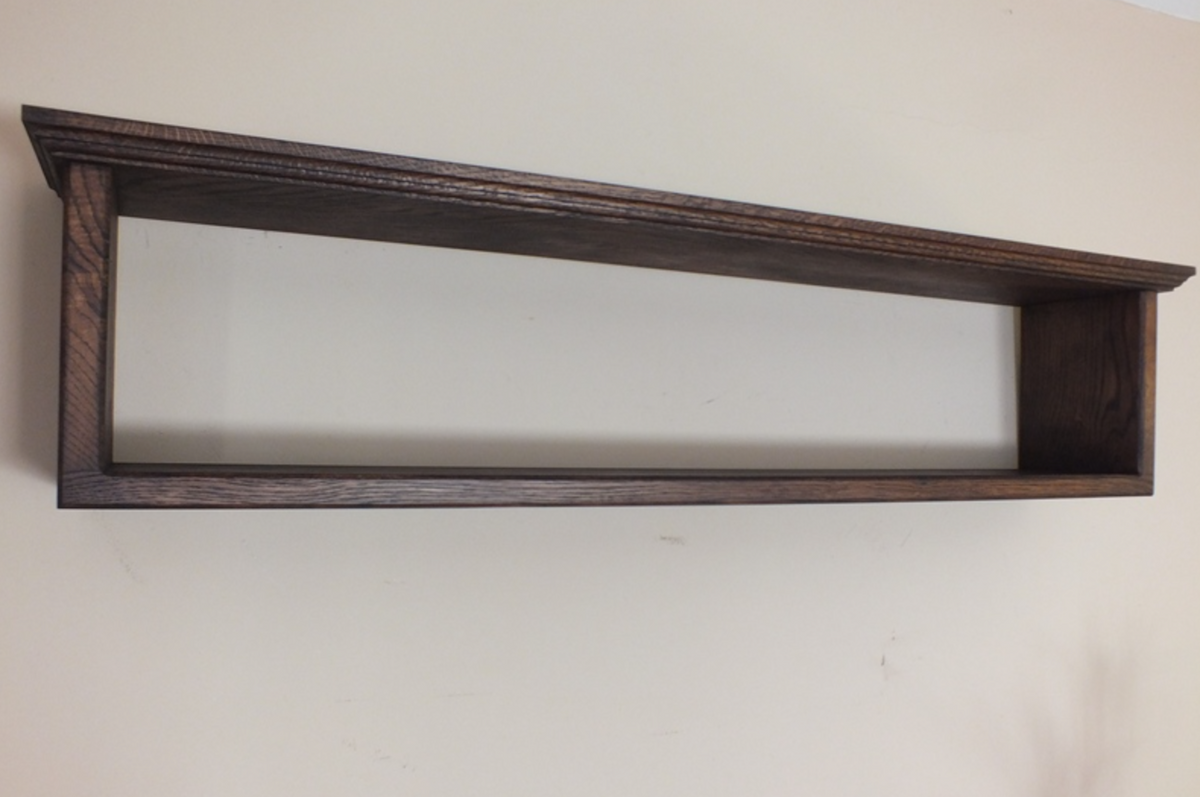 A dark brown wooden floating shelf with a simple rectangular design, mounted on a plain off-white wall.