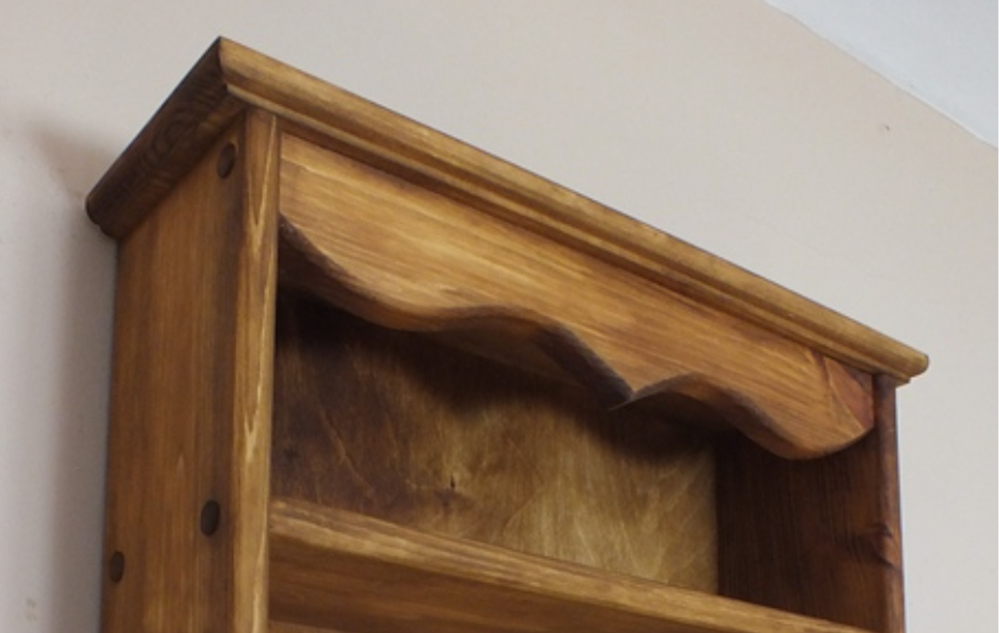 Wooden wall shelf with multiple hooks on a plain background