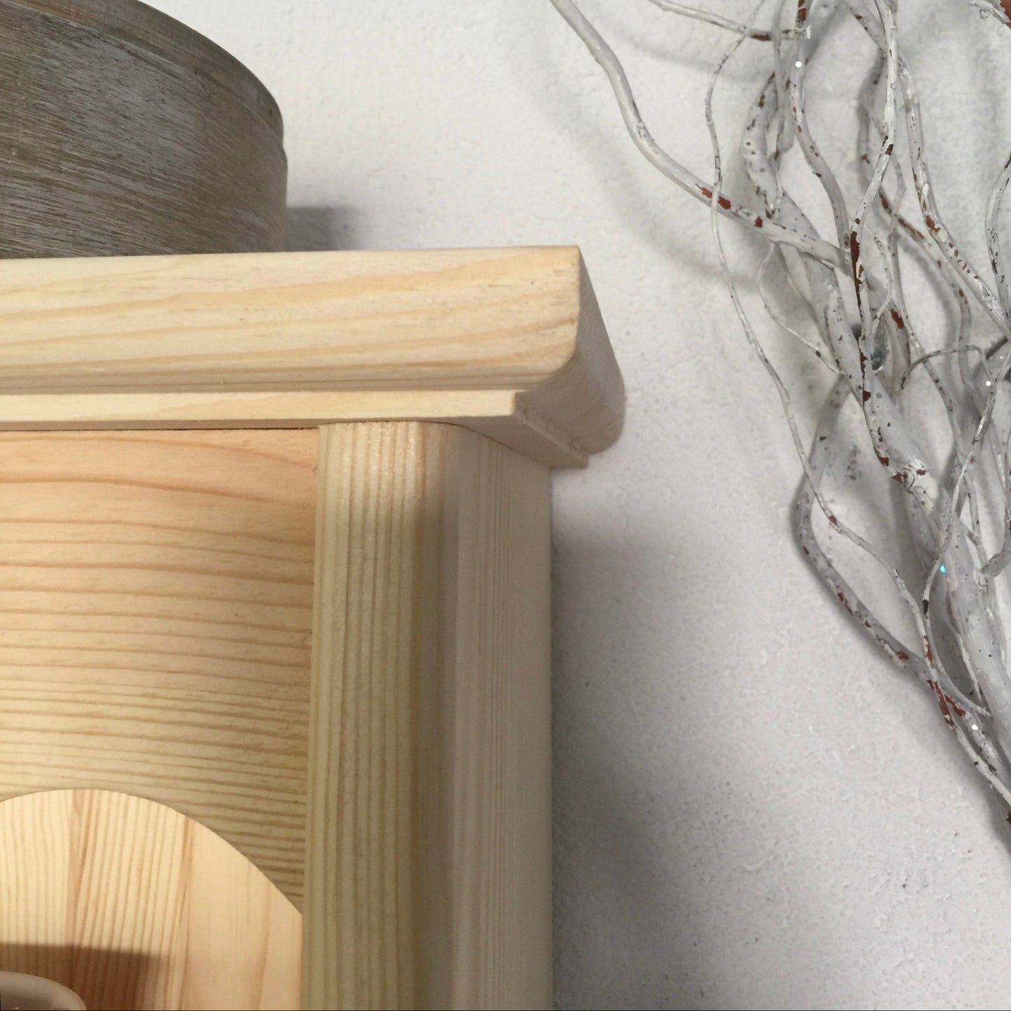 Wooden stool with a textured white wall and decorative branches in the corner