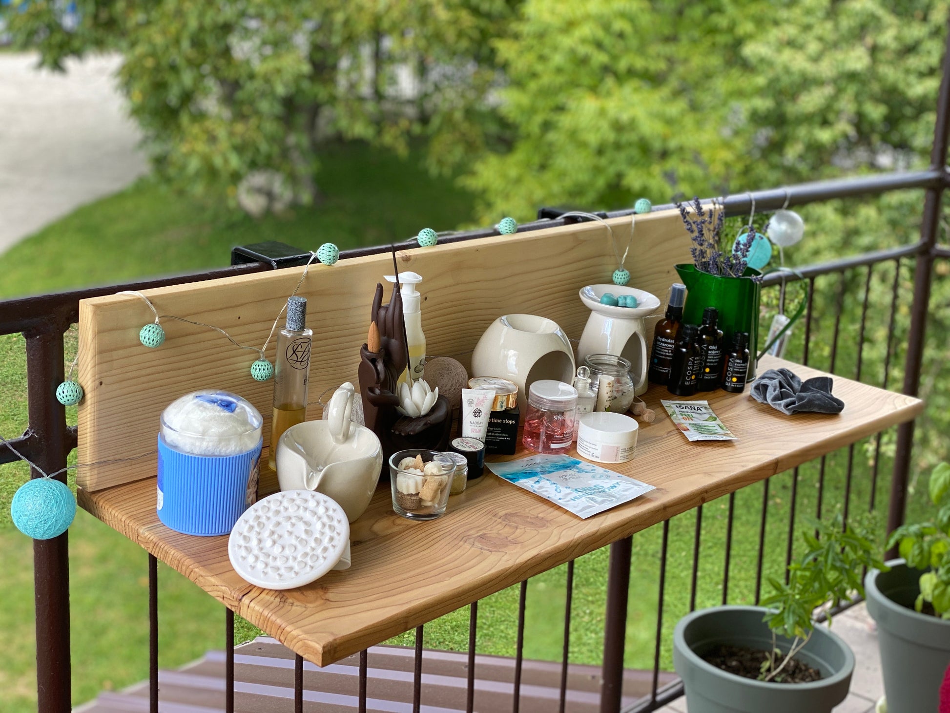 Wooden table with various items on a balcony with greenery in the background