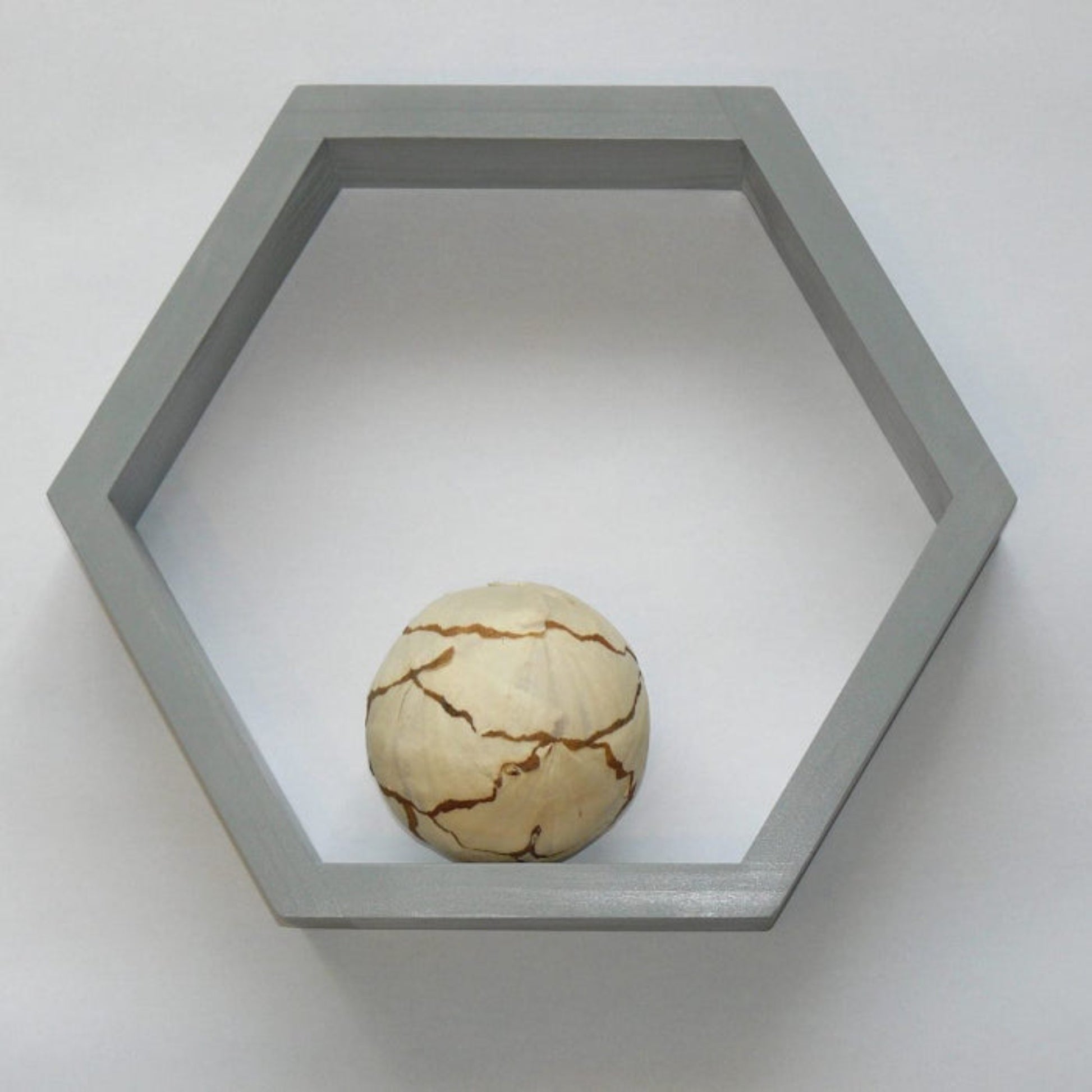 Hexagonal gray frame with a spherical object on a white background